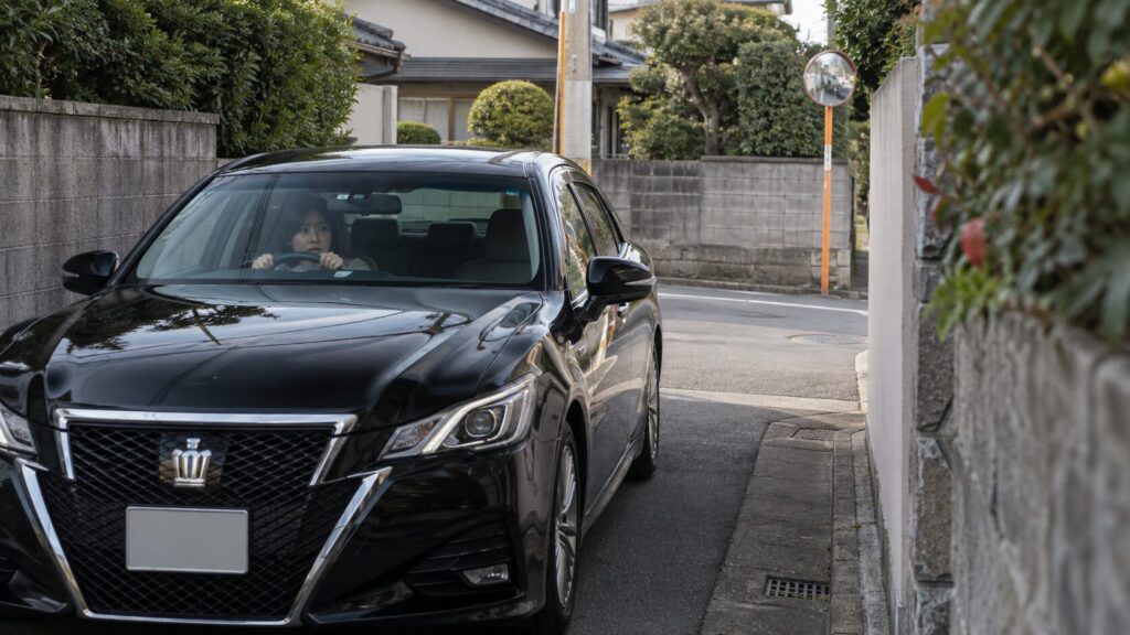 狭い住宅街でクラウンを慎重に運転する女性