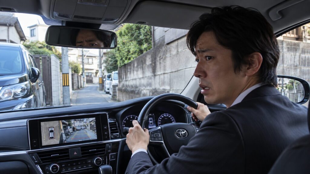 狭い道路でセダンの運転に困る男性ドライバー