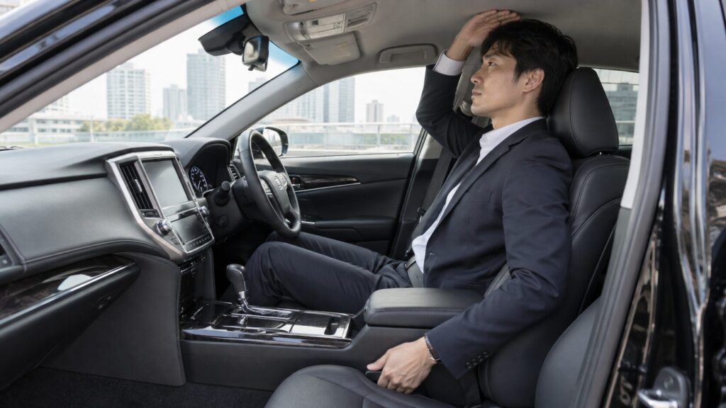 クラウンの運転席で頭上のスペースを確認する背の高い男性